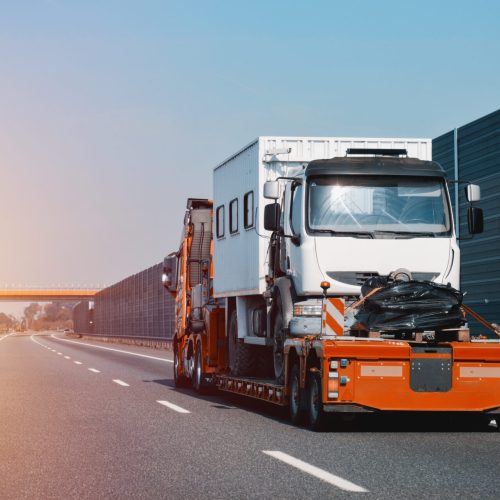 A side view of the towing truck with a brand-new commercial vehicle. Emergency roadside assistance. Vehicle Mechanical Problem on the Road.